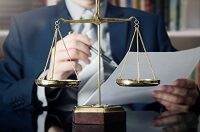 A man in a suit looking at a legal document with scales on his desk